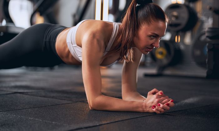 A woman focused on her workout, performing a plank exercise with determination.
